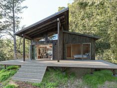 a wooden cabin with stairs leading up to it's bedroom and living area in the woods