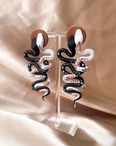 two black and white snake earrings on a stand