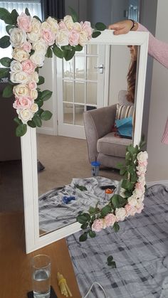 a woman standing in front of a mirror with flowers on it