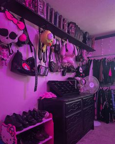 a room filled with lots of pink and black items on shelves next to a purple wall