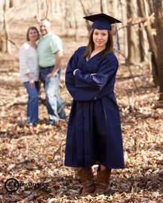 two people standing in the woods wearing graduation gowns and boots with their arms crossed