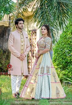 a man and woman standing next to each other in front of a palm leaf tree