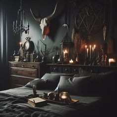 a bed with black sheets, candles and skulls on the wall above it in a dark room