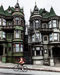 a bicyclist rides past old victorian homes