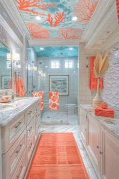 a bathroom with orange and blue decor on the ceiling, white cabinets and counter tops