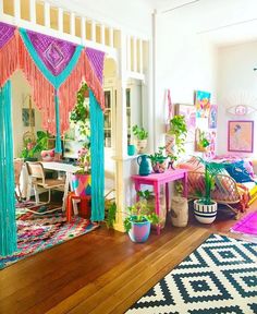 a room filled with lots of furniture and plants on top of wooden flooring next to a white wall