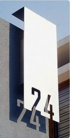 a house number sign on the side of a building with a sky in the background