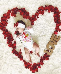 a baby laying in the shape of a heart with rose petals on it's side