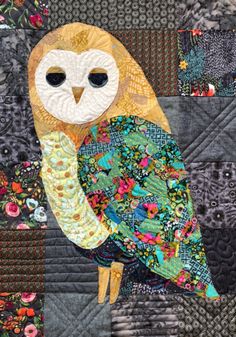 an owl sitting on top of a patchwork quilt