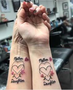 two girls with matching tattoos on their arms, one is holding the other's hand