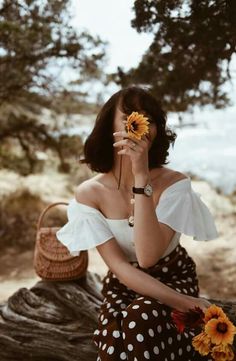 a woman in a polka dot dress holding sunflowers