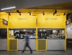 a blurry image of a person walking past a restaurant counter with yellow walls and doors