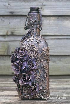 a bottle with flowers on it sitting on a wooden table