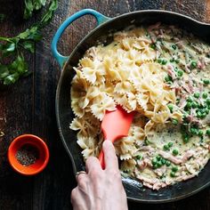 a person mixing pasta in a skillet