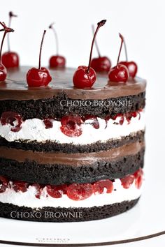 a chocolate cake topped with cherries and whipped cream