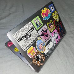 an open laptop computer covered in stickers on a white surface with a black background