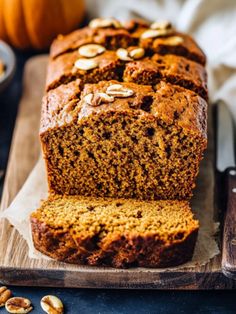 sliced loaf of pumpkin bread on top of a cutting board next to a bowl of nuts