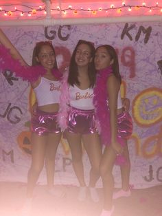 three girls dressed in pink and white posing for the camera