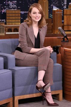 a woman sitting on top of a blue couch in front of a microphone and chair