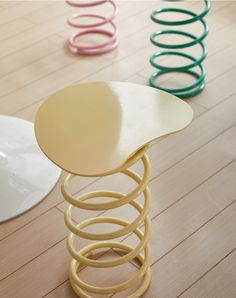 three different colored stools sitting on top of a wooden floor next to each other