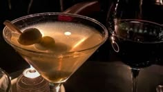 two martinis with olives in them sitting on a table