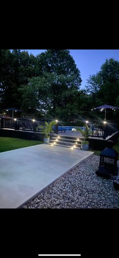 an outdoor patio with lights and steps leading up to the pool at night, surrounded by trees