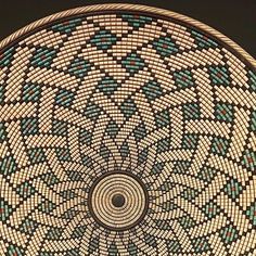 a basket that is sitting on top of a wooden table with blue and green designs