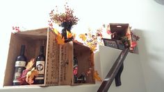 two wine bottles in wooden boxes with autumn decorations on the top and bottom, along with other items