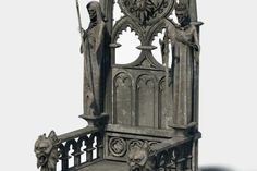 an elaborately carved bench with statues on it's sides and the top part of its frame