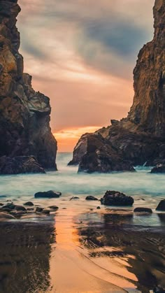 the beach is full of rocks and water at sunset or sunrise, with one rock sticking out of the ocean