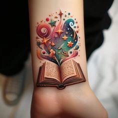 an open book tattoo on the wrist with stars and swirls coming out of it