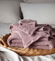 a basket filled with blankets on top of a bed