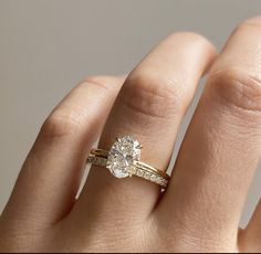 a woman's hand with a diamond ring on top of her finger and an engagement band