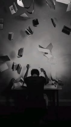 a person sitting at a desk with books falling from the ceiling