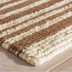 a close up of a brown and white rug on a wooden floor with wood floors