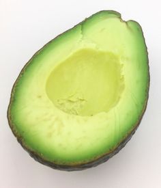 an avocado cut in half on a white surface