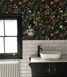 a bathroom with black and white wallpaper, sink and radiator next to the window