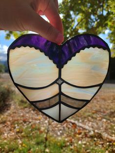 a hand holding a stained glass heart in the shape of a butterfly's wing