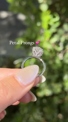 a hand holding a diamond ring with the words petal prongs on it