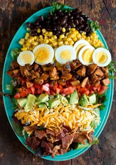 a salad with hard boiled eggs, bacon, lettuce, tomatoes, corn, black olives and dressing