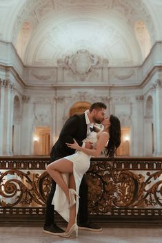 a man and woman are kissing in front of an ornate balcony with gold railings