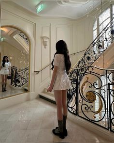 a woman standing in front of a mirror next to a stair case holding a leash