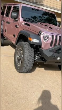 a pink jeep is parked in front of a house with a shadow on the ground