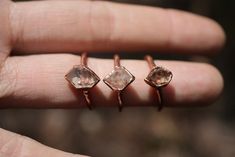 three different sized rings on someone's finger, one with an orange diamond in the middle