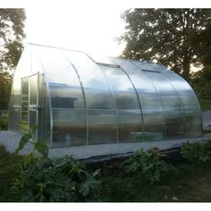 a large metal structure sitting in the middle of a field next to trees and bushes