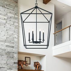 a chandelier hanging from the ceiling in a living room next to a fireplace