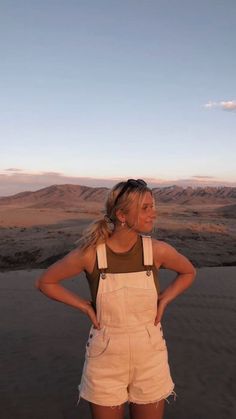 a woman standing in the desert with her hands on her hips