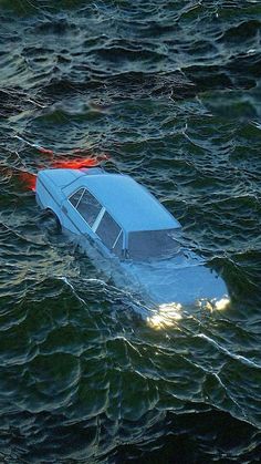 a car is floating in the middle of the ocean with red lights on it's hood