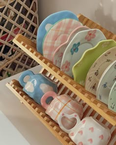 there are many plates and cups on the shelf in the store, each with different designs