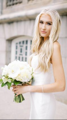 a woman in a white dress holding a bouquet of flowers